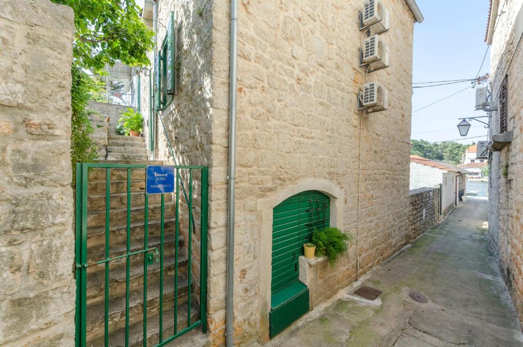 an alley with a green gate in a building at Apartments Draga in Vrboska