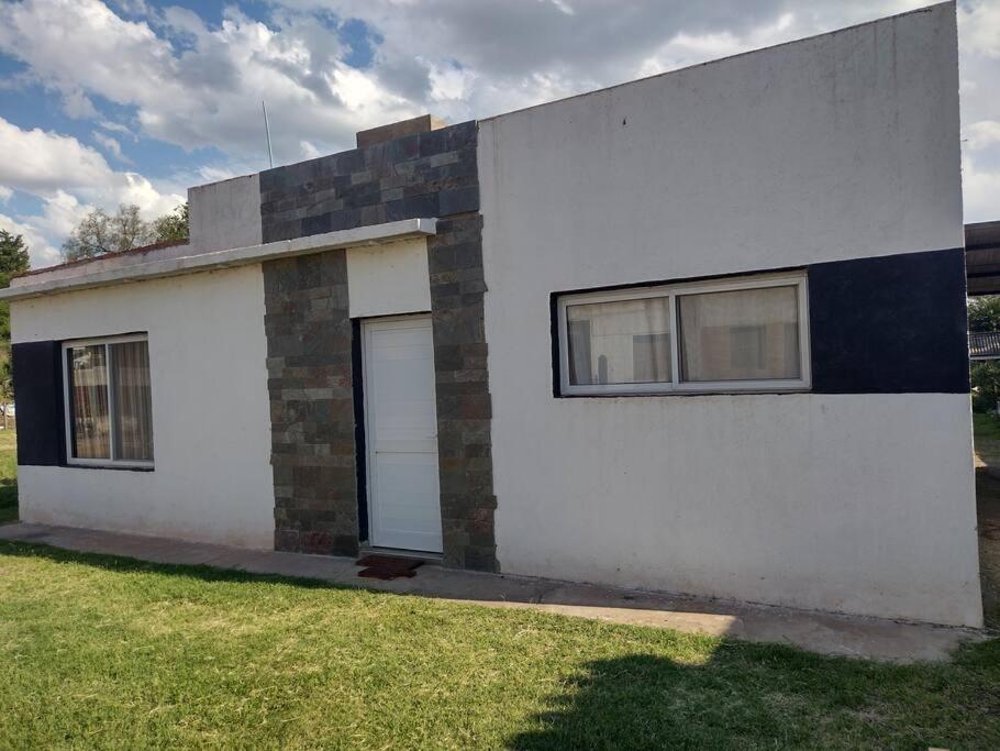 a white house with two windows and a yard at La Casita in Embalse