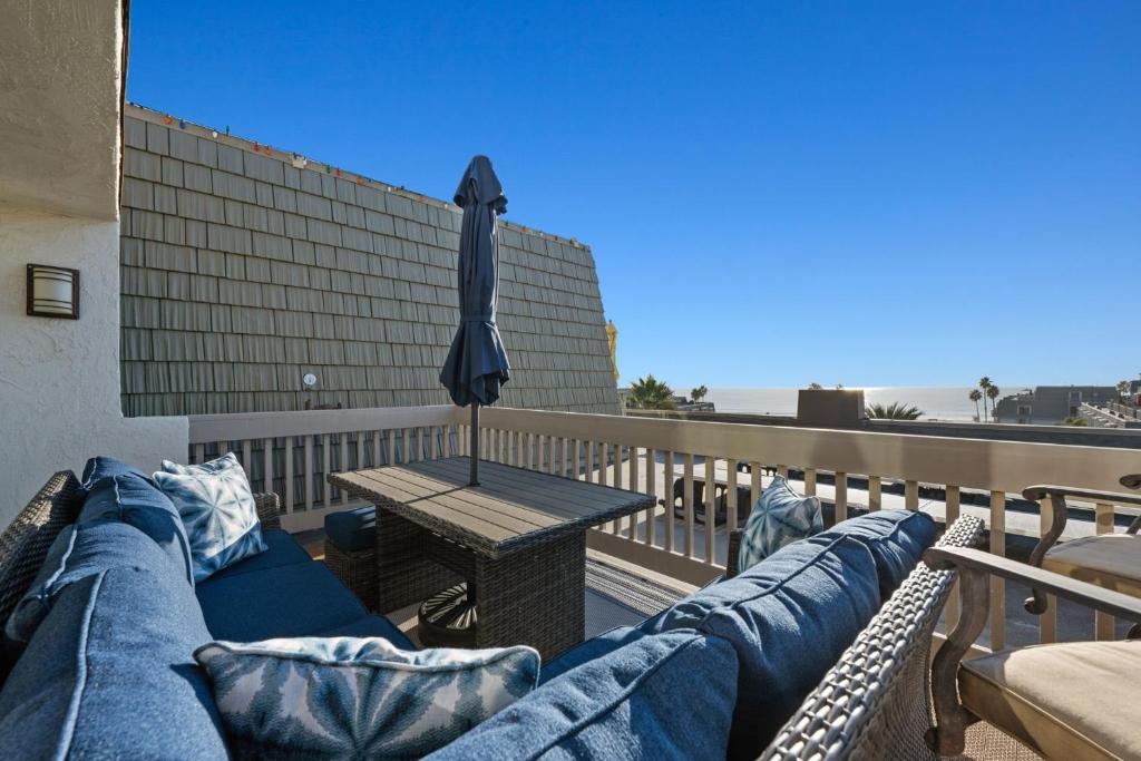 a couch on a balcony with a table and an umbrella at B302 - Barefoot Villa in Oceanside