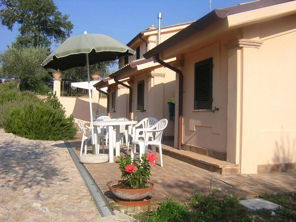 Un patio con una mesa y sillas y una sombrilla. en Apartment in a farmhouse with swimming pool, en Giano dellʼUmbria