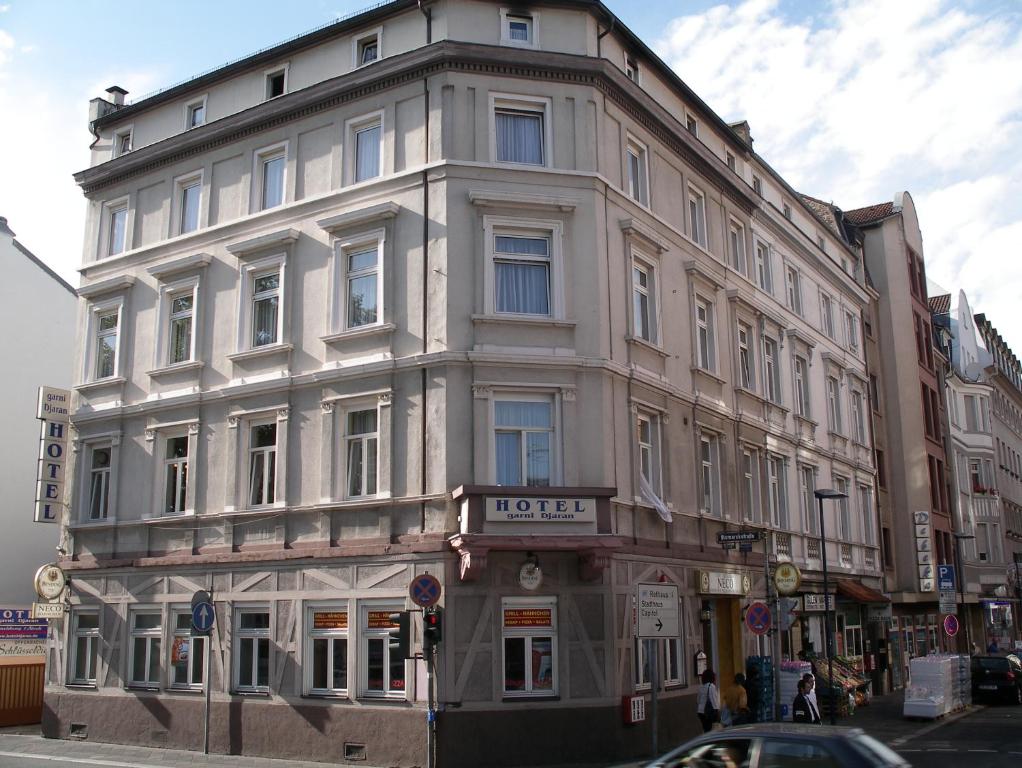 un grand bâtiment blanc au coin d'une rue dans l'établissement Hotel garni Djaran, à Offenbach-sur-le-Main