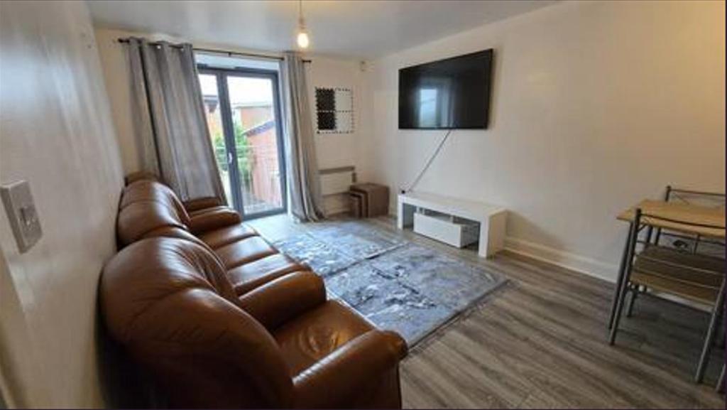 a living room with a leather couch and a television at City Bliss Great Location in Birmingham
