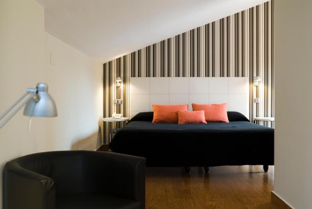 a bedroom with a black bed with two orange pillows at Posada del Almudí in Daroca