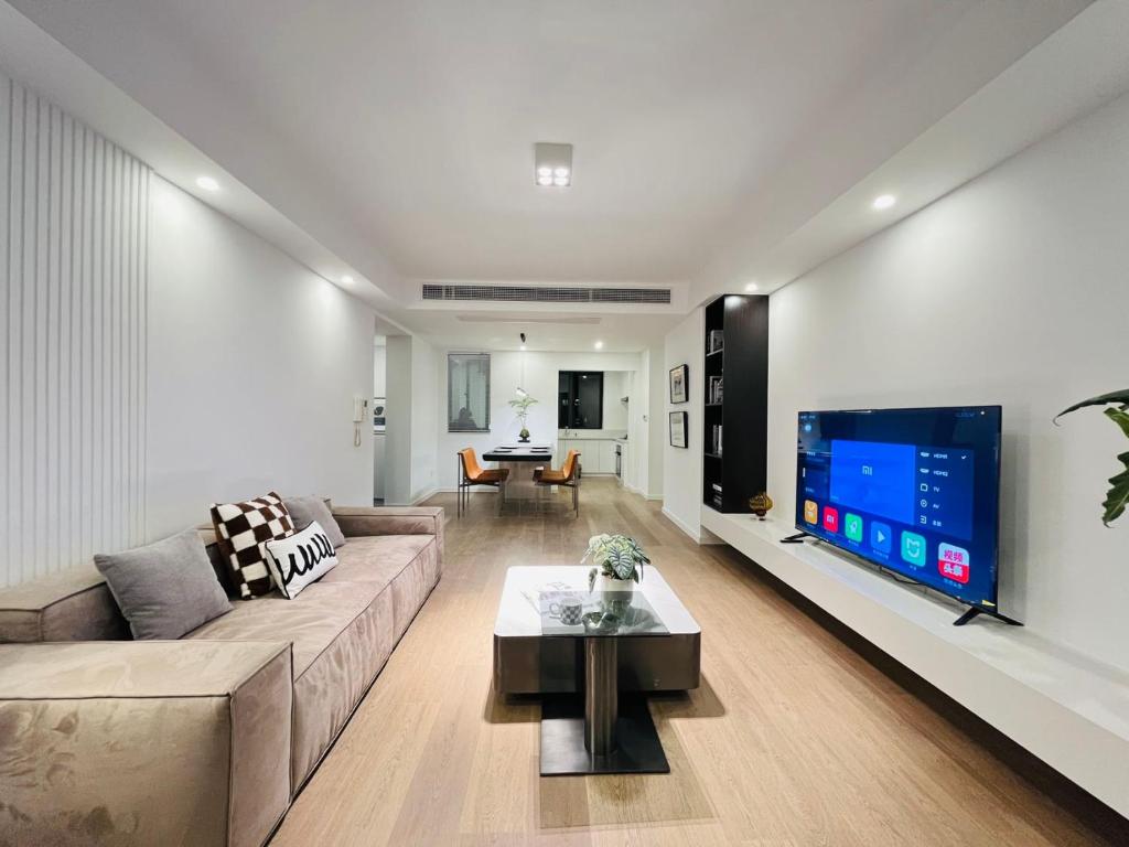 Bund Branch New west door 2 bedrooms big house في شانغهاي: غرفة معيشة مع أريكة وتلفزيون بشاشة مسطحة