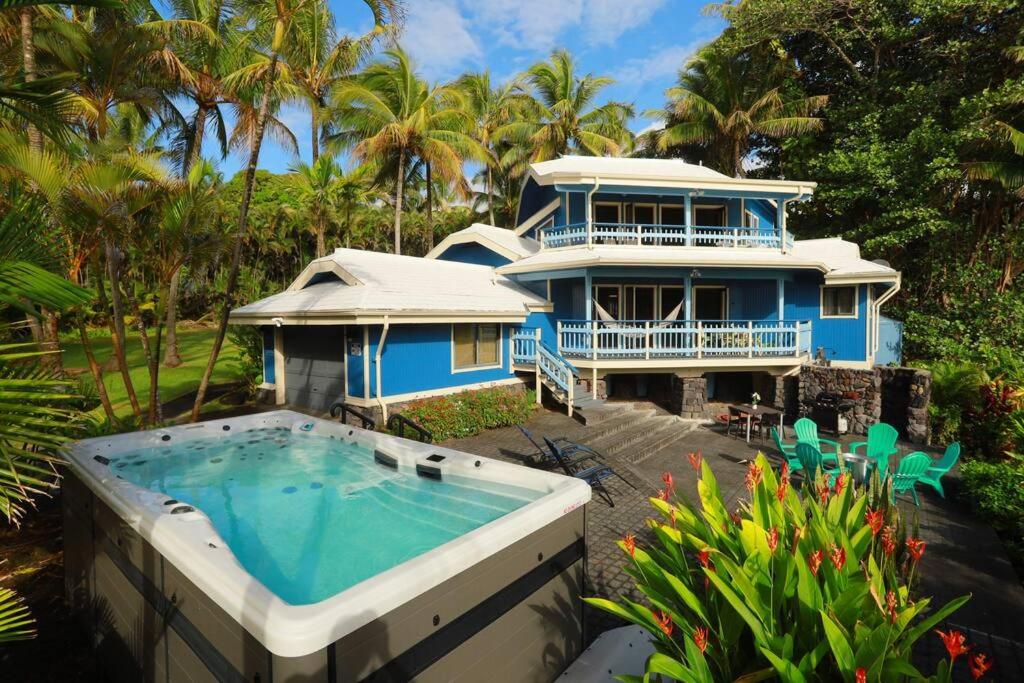 a blue house with a swimming pool in front of it at kehena black sand beach house - ocean view swim spa in Pahoa