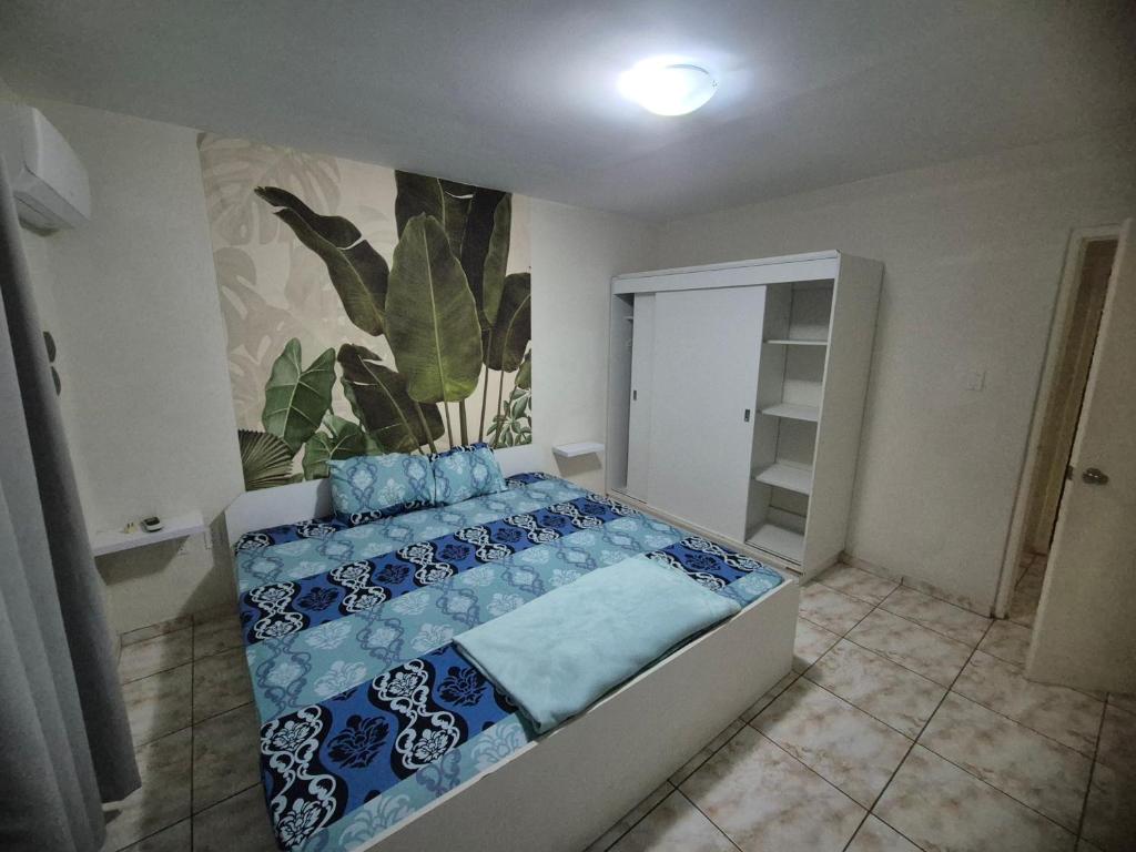 ein Schlafzimmer mit einem Bett mit blauer Bettwäsche und einem Pflanzenmilch in der Unterkunft Tahir & Tamir Apartment in Willemstad