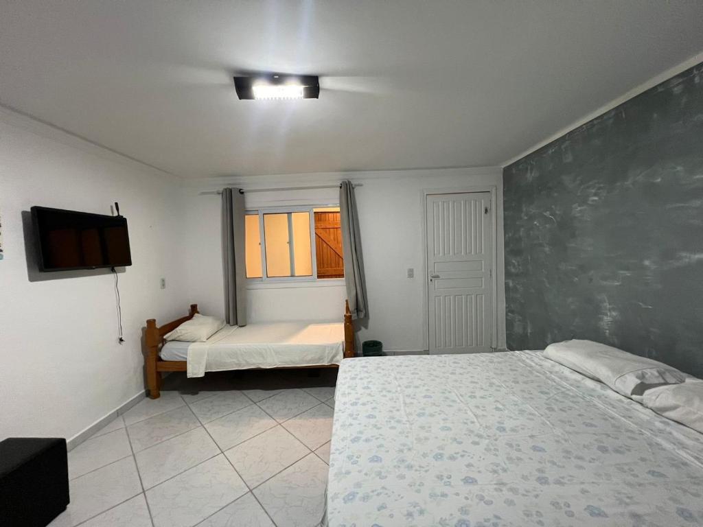 a bedroom with two beds and a tv and a window at Boas Vindas in Guarujá