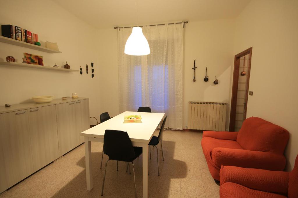 uma cozinha e sala de jantar com uma mesa e uma cadeira vermelha em Vittori Apartment em Siena