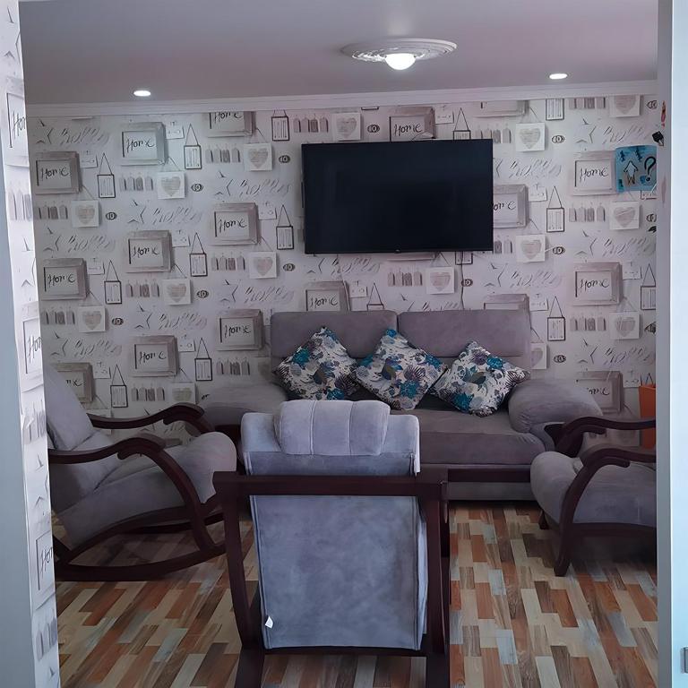 ein Wohnzimmer mit einem Sofa und einem Fernseher an der Wand in der Unterkunft Casa Vacacional Alejandria in Paipa