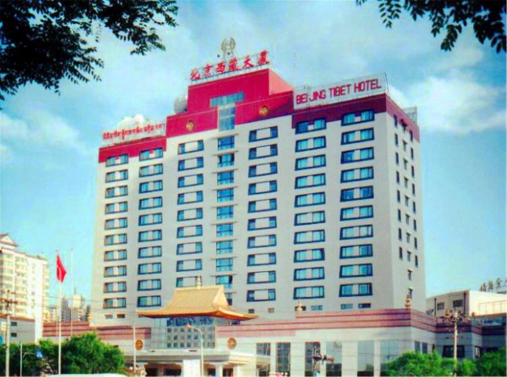 a large red and white building with a sign on it at Beijing Tibet Hotel in Beijing