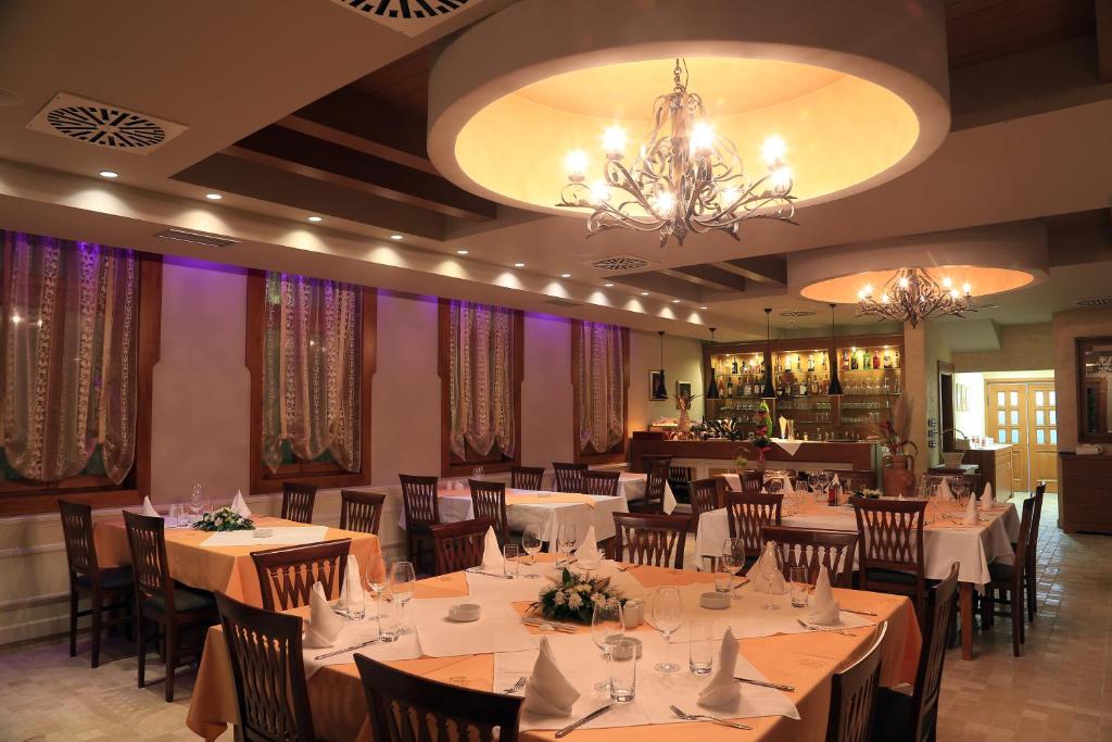 a dining room with tables and chairs and a chandelier at Hotel Village in Stari Banovci