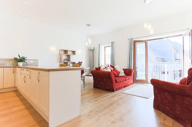 a kitchen and living room with two red chairs and a counter at Tidemill House Apartment in Falmouth