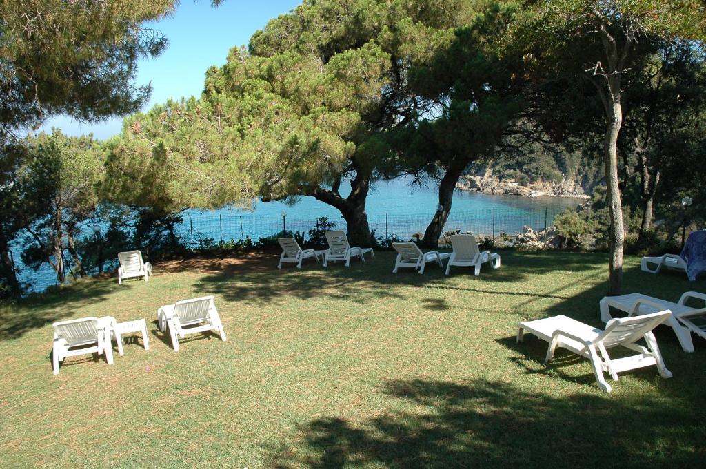 a group of chairs and tables on the grass near the water at Hotel Viticcio in Portoferraio
