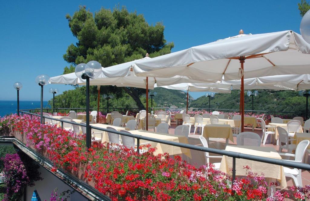 a row of tables and chairs with white umbrellas and flowers at Hotel Viticcio in Portoferraio
