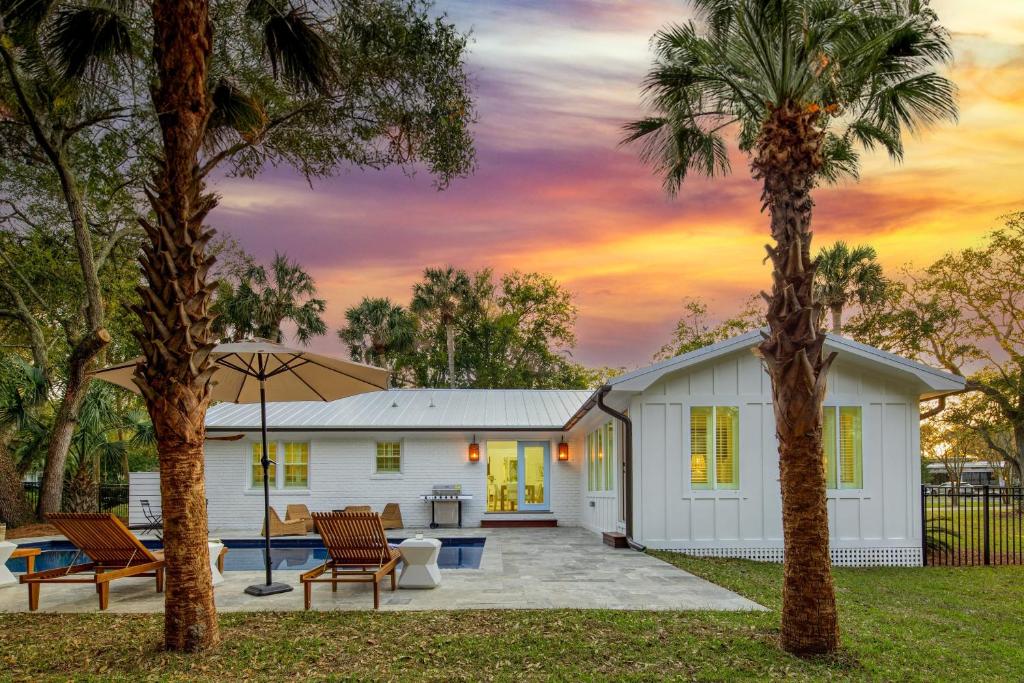 a white house with two palm trees in the yard at Sawyer by AvantStay Stunning Isle Of Palms Home w Pool in Isle of Palms