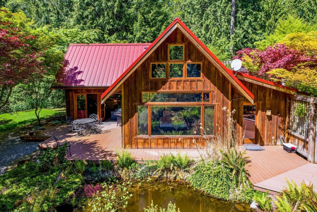 a log cabin with a red roof and a pond at Rhythm Waters by AvantStay Garden Paradise Pond in Langley