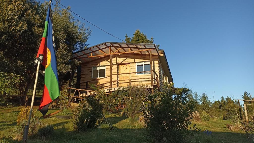 een boomhut met een vlag ervoor bij Cabañas y Agroturismo El Trolofken in Pocuno