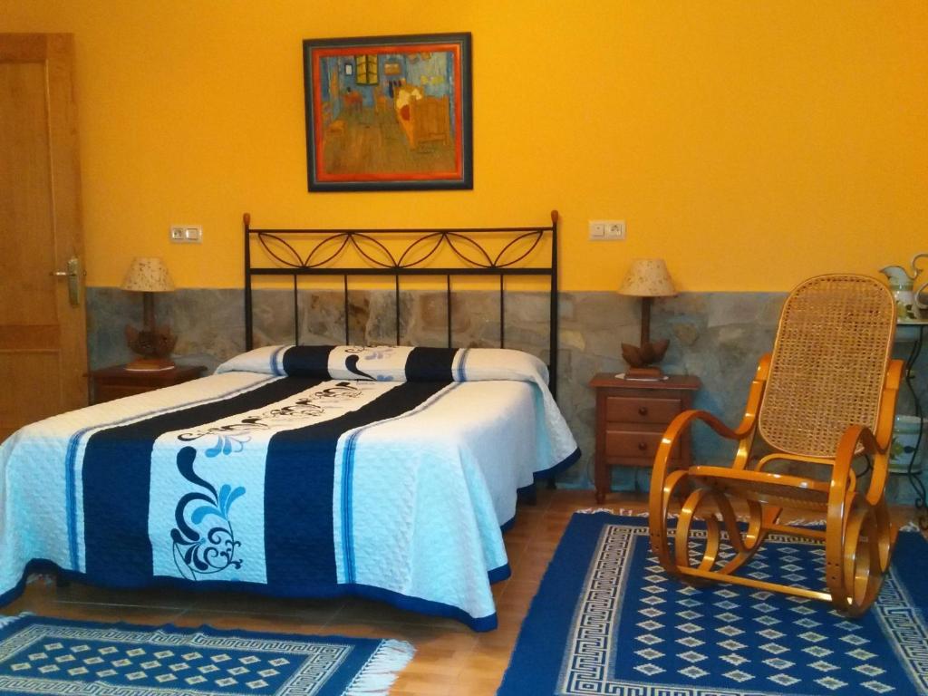 a bedroom with a bed and a chair and two rugs at Apartamentos Rurales Casa El Caminero in Merás
