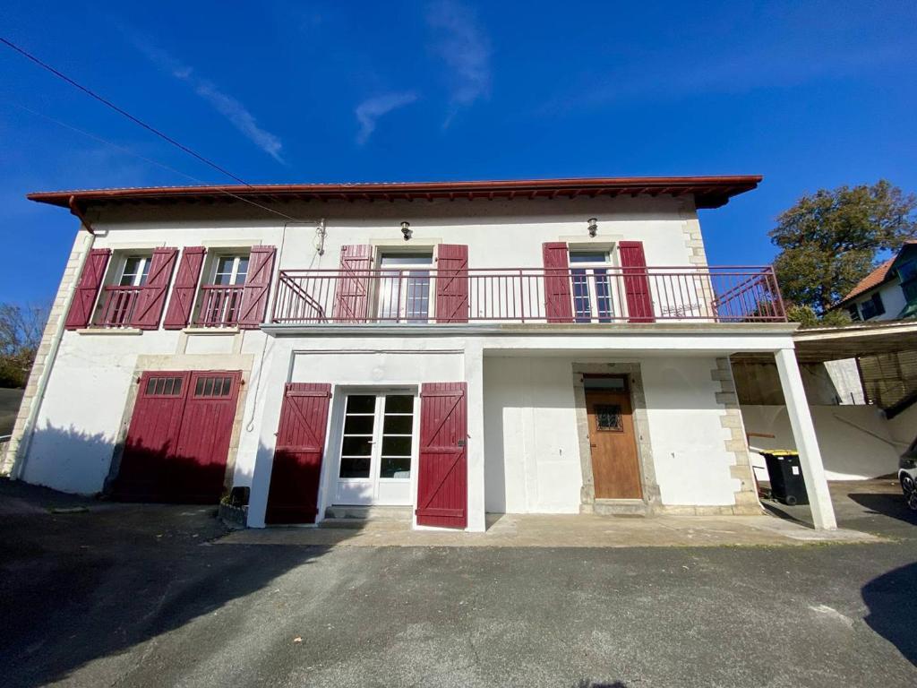 a white house with red doors and a balcony at T2 charmant à Cambo-les-Bains, proche Thermes, WIFI, 2 couchages - FR-1-495-146 in Cambo-les-Bains