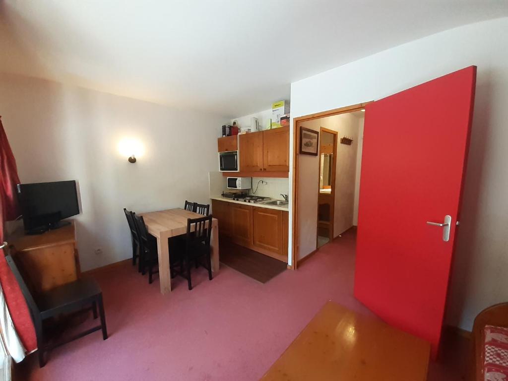 une chambre avec une porte rouge et une cuisine avec une table dans l'établissement À louer à Valfréjus, 310 rue du Cheval Blanc - FR-1-561-121, à Modane