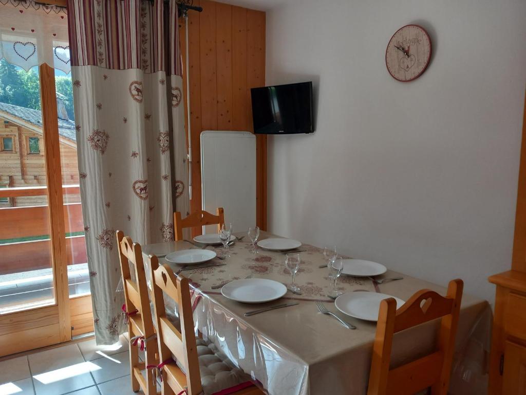 une table à manger avec des chaises et une horloge murale dans l'établissement Appartement 6 pers, proche pistes & navette, parking - FR-1-467-144, au Grand-Bornand