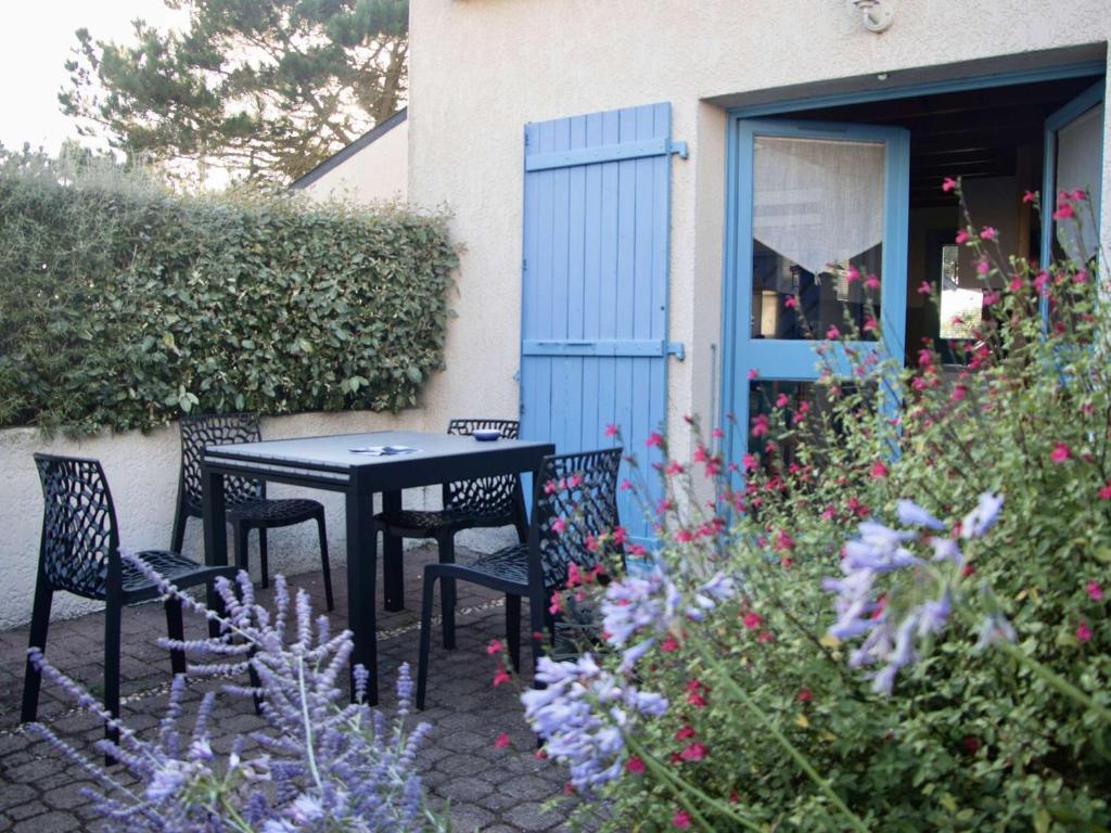 une table et des chaises dans un jardin fleuri dans l'établissement Erdeven, Maison cosy 3 pièces avec terrasse et parking, proche plage - FR-1-479-174, à Erdeven