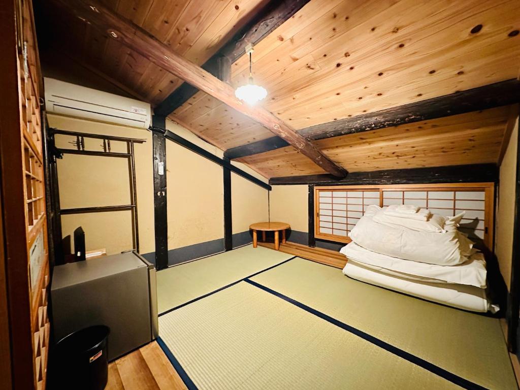 Pokój z łóżkiem w pokoju z drewnianym sufitem w obiekcie Nagomi-Ryokan Yuu w mieście Kioto