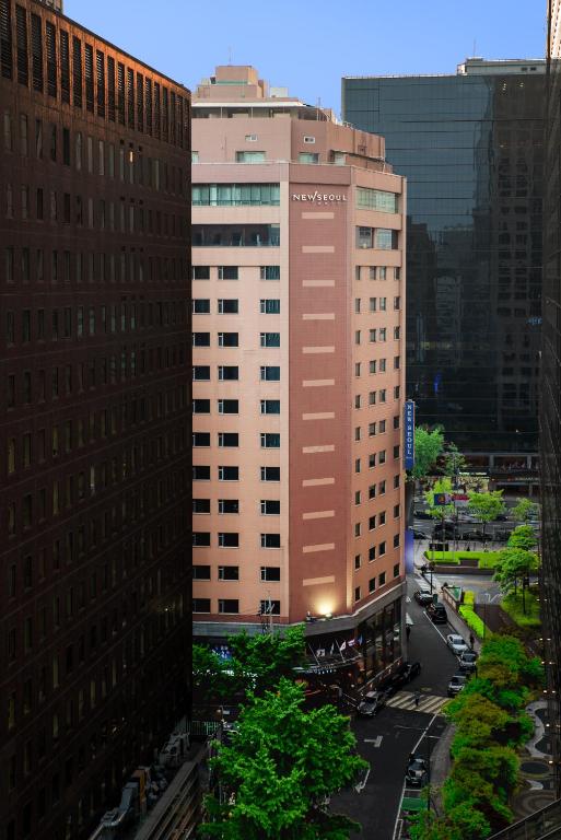 a tall tan building with a sign on it at New Seoul Hotel Myeongdong in Seoul