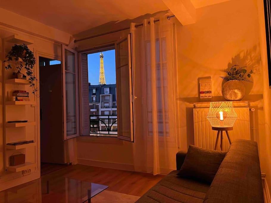 a living room with a window with a view of the eiffel tower at Le Point d'Eiffel - Au Cœur de Grenelle in Paris