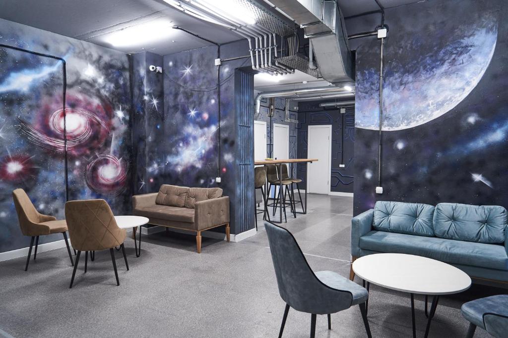 a room with a couch and tables and chairs at Gagarin Capsule Hotel in Almaty