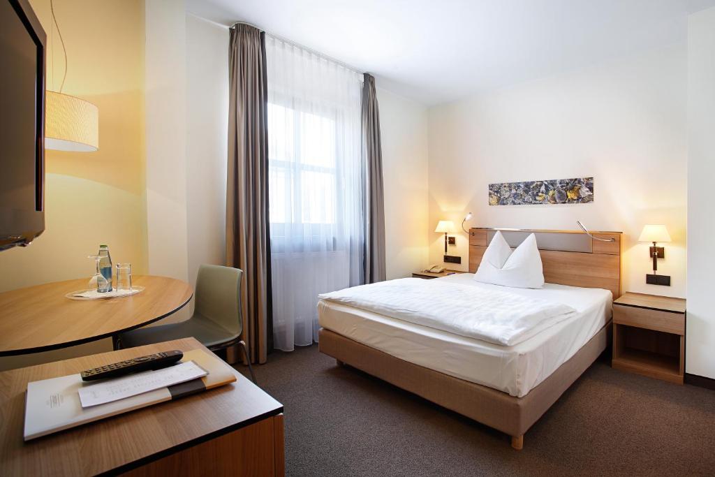 a hotel room with a bed and a desk with a computer at Hotel am Jakobsmarkt in Nuremberg