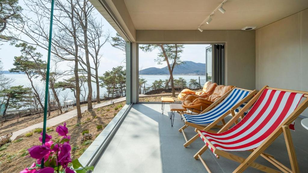 a living room with chairs and a view of the water at Ganghwado Lafamilia Pension in Incheon