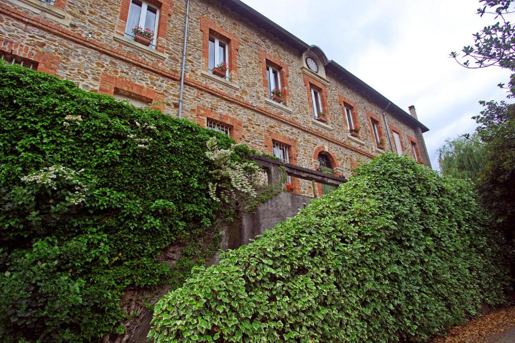 un grande edificio in mattoni con cespugli di fronte di Château Lou Cante Perdrix a La Vernarède