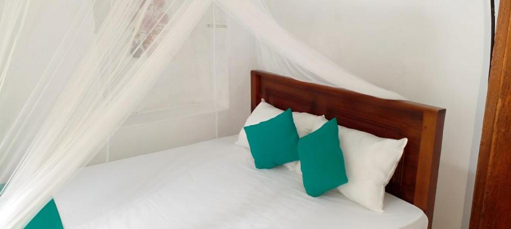 ein Bett mit grünen und weißen Kissen darauf in der Unterkunft Shine View in Dikwella