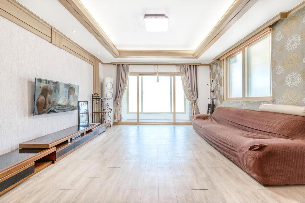 a large living room with a couch and a tv at Samcheok Greenhyang Pension in Samcheok