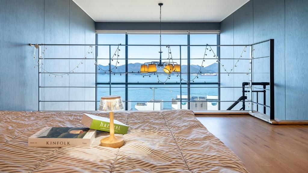 a bedroom with a bed with a book and a lamp at Namhae Byeol grigo namhae Pension in Namhae