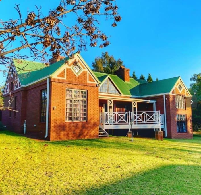 una gran casa de ladrillo con techo verde en Clarens Charm, en Clarens