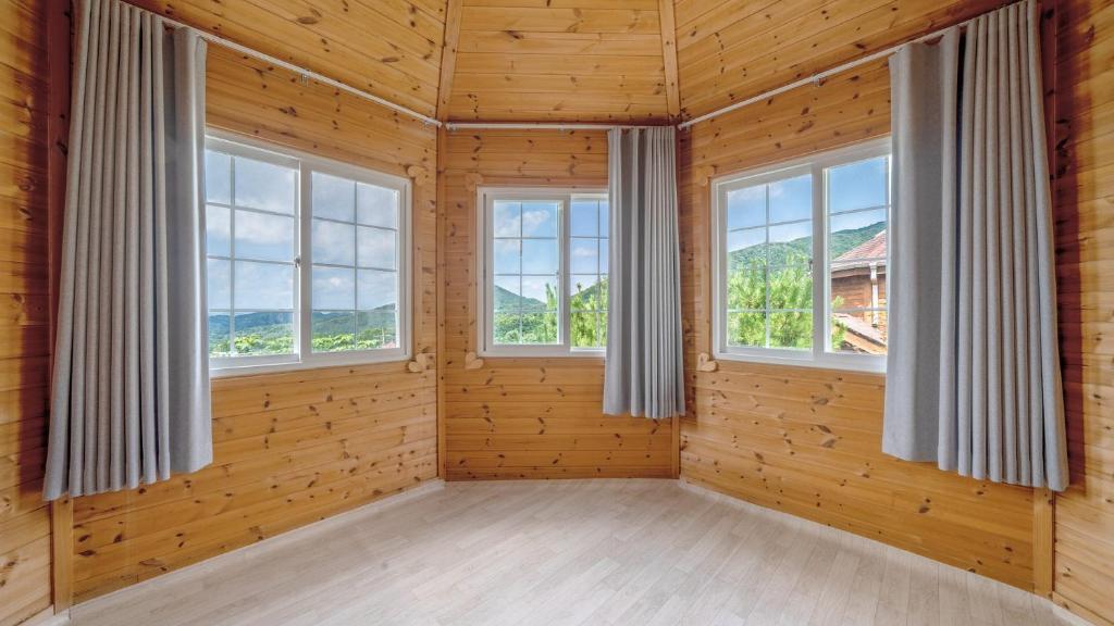 a room with three windows in a wooden house at Paju Sugavill Agyeon dongban Pension in Paju