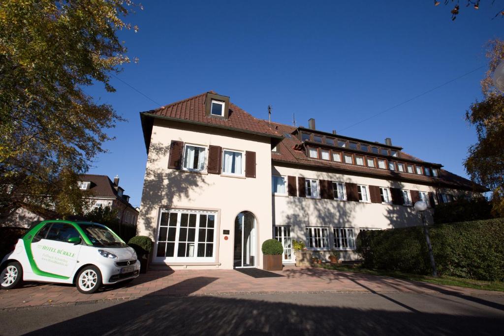 a white house with a car parked in front of it at Hotel Bürkle in Fellbach