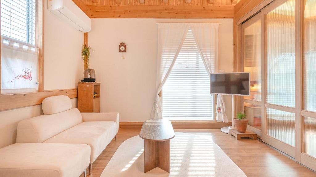 a living room with a couch and a tv at Gangneung Gangmunsosodam Pension in Gangneung