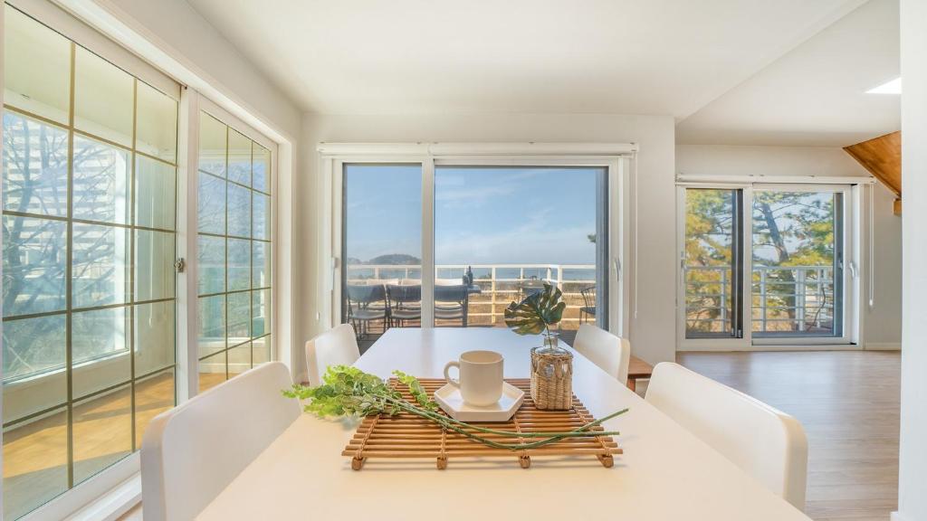 a dining room with a table and chairs and large windows at Boryeong Thirasel Pension in Boryeong