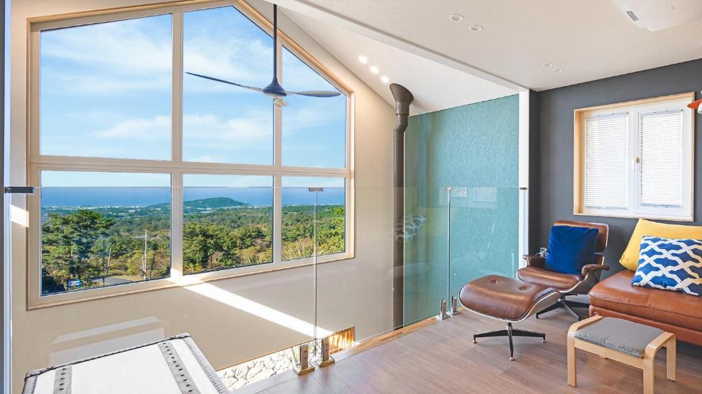 a room with a large window and a couch and chair at Jeju Sogilrian974 Pension in Jeju