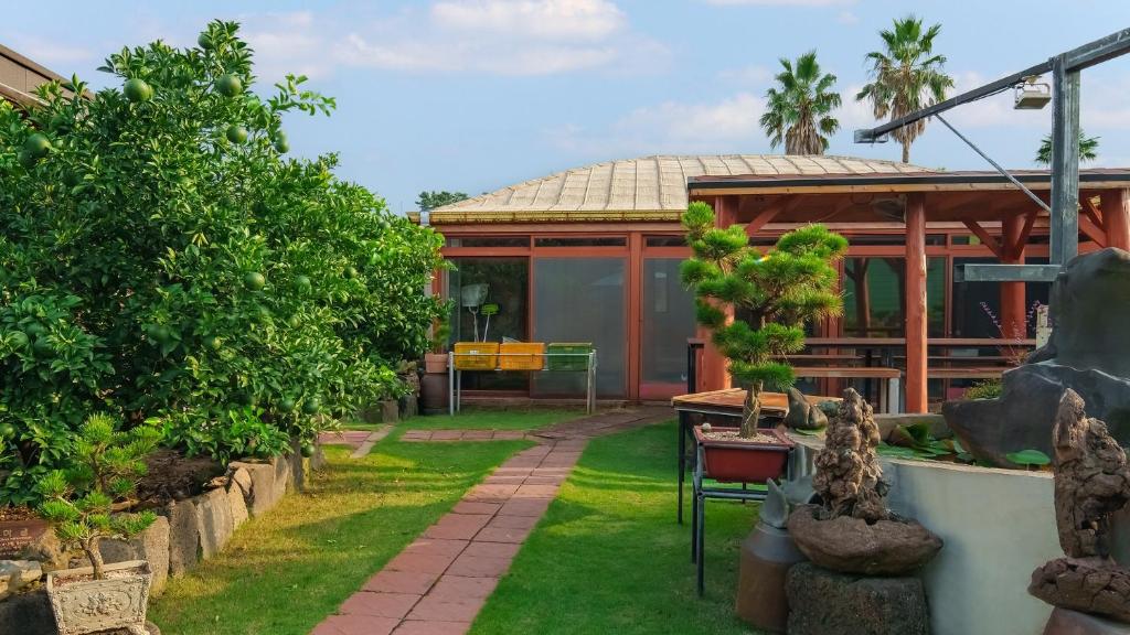 un giardino con un edificio sullo sfondo di Jeju Jeonwonsaenghwal Diorem Pension a Jeju
