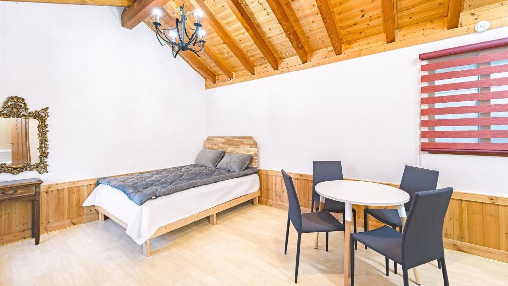 a bedroom with a bed and a table and chairs at Gangneung Sinami68 Pension in Gangneung