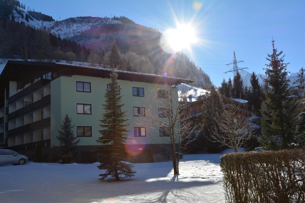 a building in the snow with the sun behind it at Appartement Kaprun4You in Kaprun