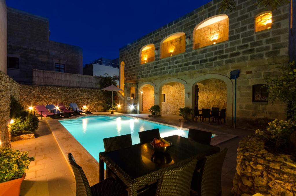 a pool with a table and chairs next to a building at Ta'Filomena in Xagħra