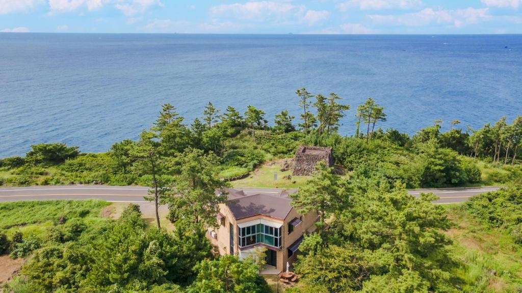 an aerial view of a house on a hill next to the ocean at jeju oceancliffcottage in Jeju