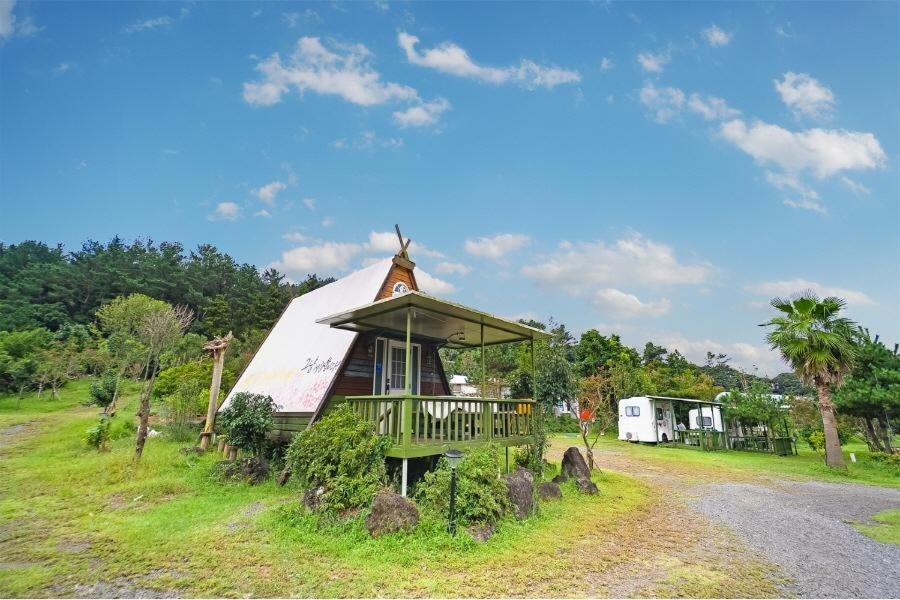 a small house with a porch on a field at Seogwipo Campa jeju in Seogwipo