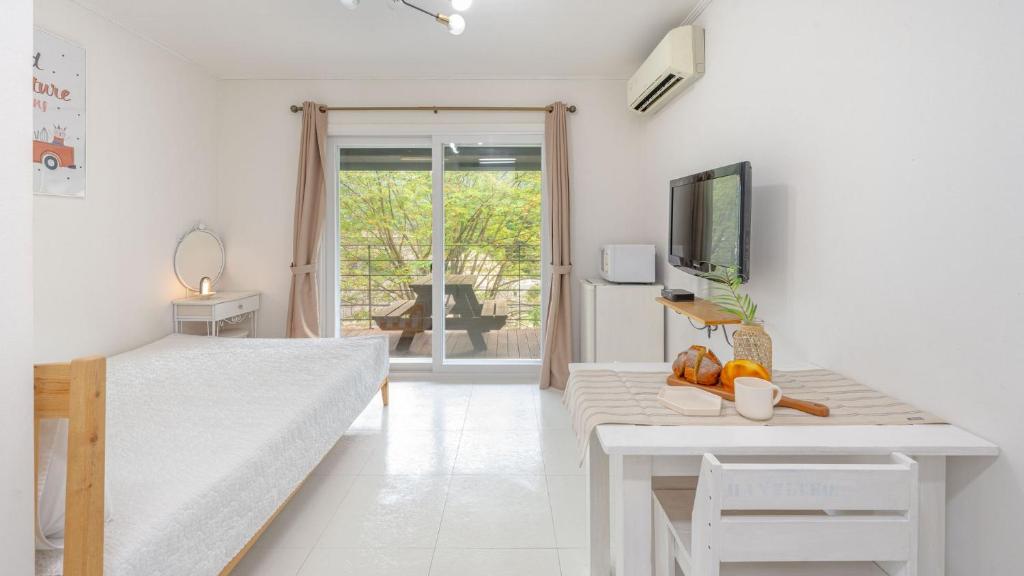 un soggiorno bianco con tavolo e TV di gapyeong hanulteo pension a Gapyeong