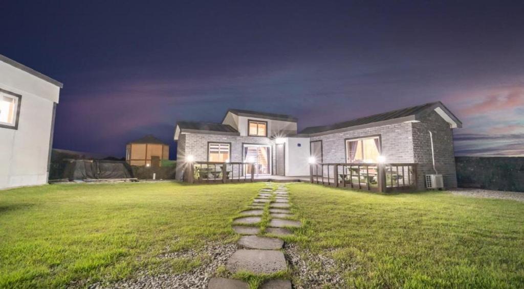 a large house with a grass yard at night at jeju bijalim pension in Jeju